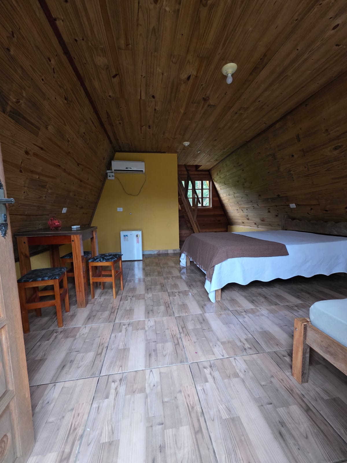 Interior de um chalé com cama, mesa e itens de apoio